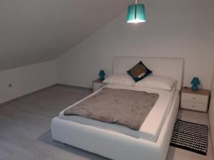 ein Schlafzimmer mit einem weißen Bett und einem Nachttisch in der Unterkunft Apartman Mohenski in Zagreb