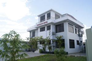 a white building with palm trees in front of it at B10 Airport Lodge in Dar es Salaam