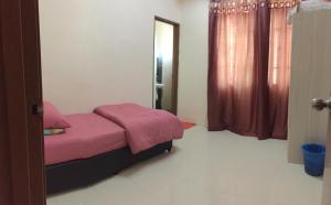 Schlafzimmer mit einem Bett mit rosa Bettwäsche und einem Spiegel in der Unterkunft Lily Homestay @ Kangar, Perlis in Kangar