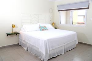 een wit bed in een witte slaapkamer met een raam bij Casa Alessandra 1bdr in Palm-Eagle Beach