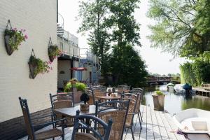 ein Restaurant mit Tischen und Stühlen neben einem Fluss in der Unterkunft De Vooroever in Wervershoof