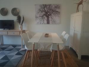 ein Esszimmer mit einem Tisch und Stühlen sowie einem TV in der Unterkunft Tangled Tree Cottage in Roodepoort