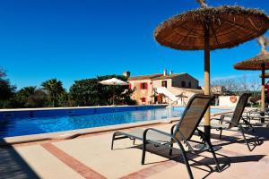 una piscina con sillas y sombrillas junto a una piscina en Finca Ses Cases Noves, en Sant Llorenç des Cardassar