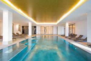 ベルガーエンデ・レートヴィッシュにあるAparthotel Waterkant Suites 2-33 mit Pool, Sauna und Meerblickのホテルのスイミングプール(椅子、天井付)