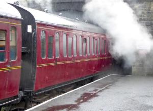 a red train with smoke coming out of the windows at BELLE VUE - SKIPTON in Skipton