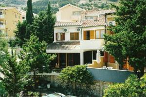 una gran casa blanca con árboles delante de ella en Apartments Olea, en Baška