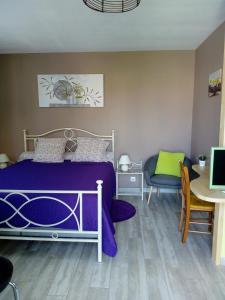 a bedroom with a purple bed and a table and a desk at Les mouettes in Les Herbiers