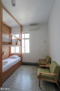 a bedroom with bunk beds and a chair and a bed and a window at Mayhow Donghe in Donghe