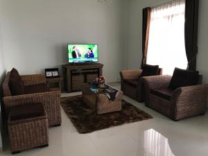 sala de estar con sillas de mimbre y TV en Kensington Villa en Bongkor