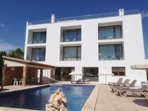 a white building with a swimming pool in front of it at Apartamentos Villa Primera in Cala Figuera