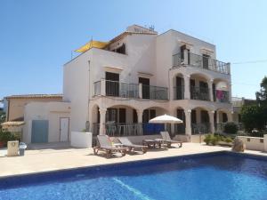 a villa with a swimming pool in front of a house at Apartamentos Villa Primera in Cala Figuera
