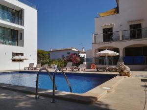 a swimming pool in front of a building at Apartamentos Villa Primera in Cala Figuera