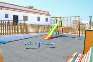 a playground with a slide and a swing set at New renovated duplex near the ocean located in Tenerife Sur in Costa Del Silencio