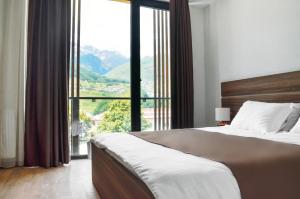 a bedroom with a large bed and a large window at Mount Inn Kazbegi in Stepantsminda