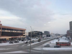 a busy city street with cars and buildings in the snow at Apart Auezov street City Centr in Ustʼ-Kamenogorsk