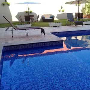 a swimming pool with blue water and an umbrella at Solarium Park Hotel in Adamantina