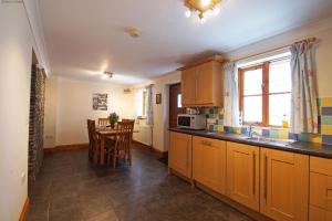 una cocina con armarios de madera y una mesa con sillas. en Gwarffynnon, en Lampeter