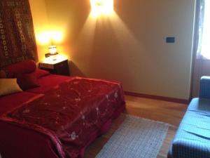 a bedroom with a red bed and a blue couch at Il Ciliegio in Imer