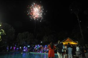 um grupo de pessoas em pé em frente a uma piscina com fogos de artifício em Sayonara Villaggio Club em Nicotera Marina