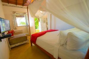 a bedroom with a white bed with a canopy at Rio Da Barra Villa Hotel in Trancoso