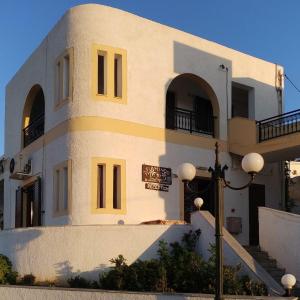 a white building with a yellow stripe on it at Flamingo Apartments in Palekastron