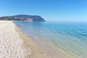 a beach with blue water and a mountain in the background at Hotel Galassi in Numana