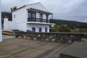 a white house with a balcony and a wooden deck at Susete Village in São Roque do Pico