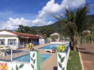蘭巴里的住宿－Pousada São Pedro，一座带椅子的游泳池,一座棕榈树旁边