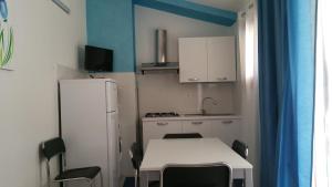 a kitchen with a white table and a white refrigerator at CASA VACANZE DEL GOLFO 2 in Castellammare del Golfo