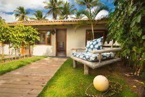 a bench sitting in the grass in front of a house at Rio Da Barra Villa Hotel in Trancoso