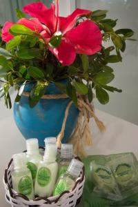 a vase with a flower and a basket of soap and shampoo at Rio Da Barra Villa Hotel in Trancoso