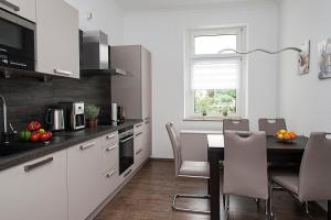 a kitchen with white cabinets and a table and chairs at Ferienwohnung am Freizeitpark Bärenloch in Solingen
