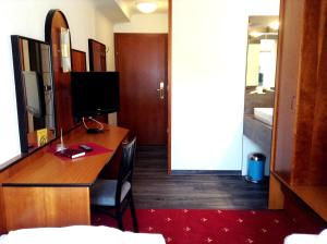 a room with a desk with a television and a bedroom at Hotel Gasthof Sonne in Aschach an der Donau