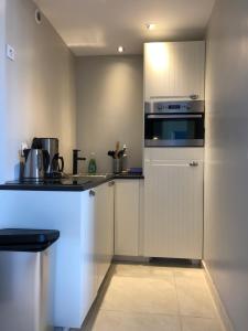 a kitchen with white cabinets and a stove top oven at La Plage d'Or in Vierville-sur-Mer