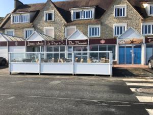 un restaurant en face d'un bâtiment dans l'établissement La Plage d'Or, à Vierville-sur-Mer