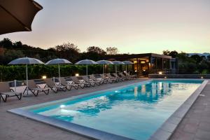 una piscina con sillas y sombrillas y un edificio en Firriato Hospitality Cavanera Etnea Resort & Wine Experience, en Castiglione di Sicilia