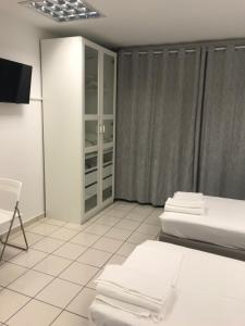Habitación blanca con 2 camas y TV. en Port of Corfu Apartment en Corfú