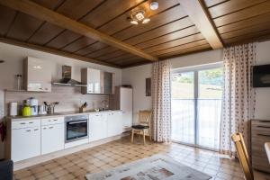 a kitchen with white cabinets and a large window at Gailtal Panorama in Kötschach