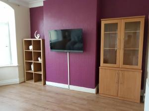 a living room with a tv on a purple wall at Central Location Preston 2 in Preston