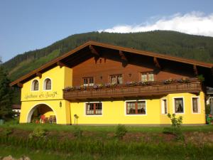a yellow and brown building with a balcony at Landhaus St. Georg in Sankt Martin am Tennengebirge