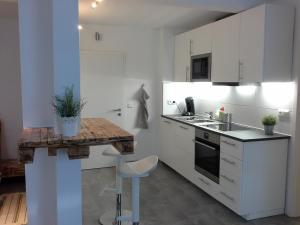 une cuisine avec des placards blancs et un comptoir en bois dans l'établissement Alles Paletti mit Klimaanlage, à Wittemberg