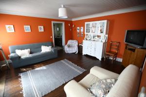 a living room with orange walls and a blue couch at Casa do Lonho in Arouca