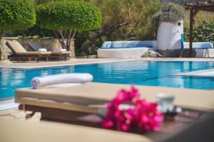 a pool with a bed and a table with pink flowers at Sitia Oceanides in Sitia