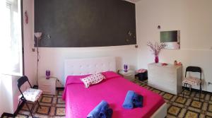 a bedroom with a pink bed and two chairs at Casa Sabrina in Lipari