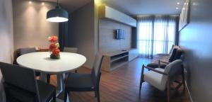 Gray Home Maceio - Condominio JTR في ماسيو: غرفة معيشة مع طاولة طعام وكراسي