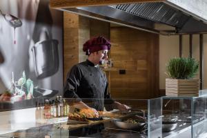 a chef standing in a kitchen preparing food at Family Hotel Adriana in Ledro