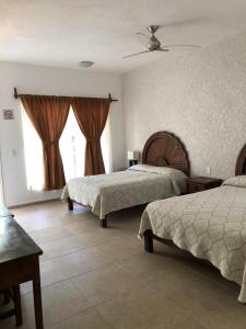a hotel room with two beds and a window at Hotel SKY & PALMS in Xochitepec