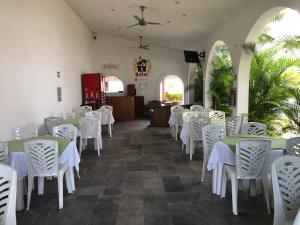uma sala de jantar com mesas brancas e cadeiras brancas em Hotel SKY & PALMS em Xochitepec