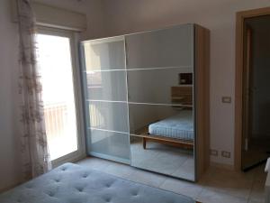 a large glass cabinet in a room with a bed at Appartamento centralissimo Marina di Ragusa in Marina di Ragusa