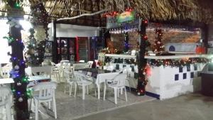 un restaurante con mesas y sillas blancas y adornos navideños en Hotel Katylú, en Tolú